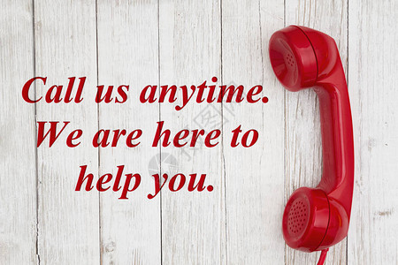 随时打电话给我们我们在这里帮助发短信与旧红色电话听筒在风湿的白图片