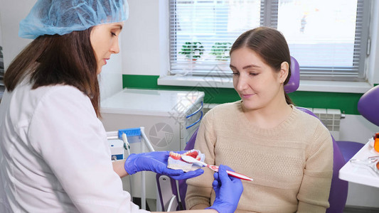 女牙医用下巴模型向病人展示如何用牙刷妥图片