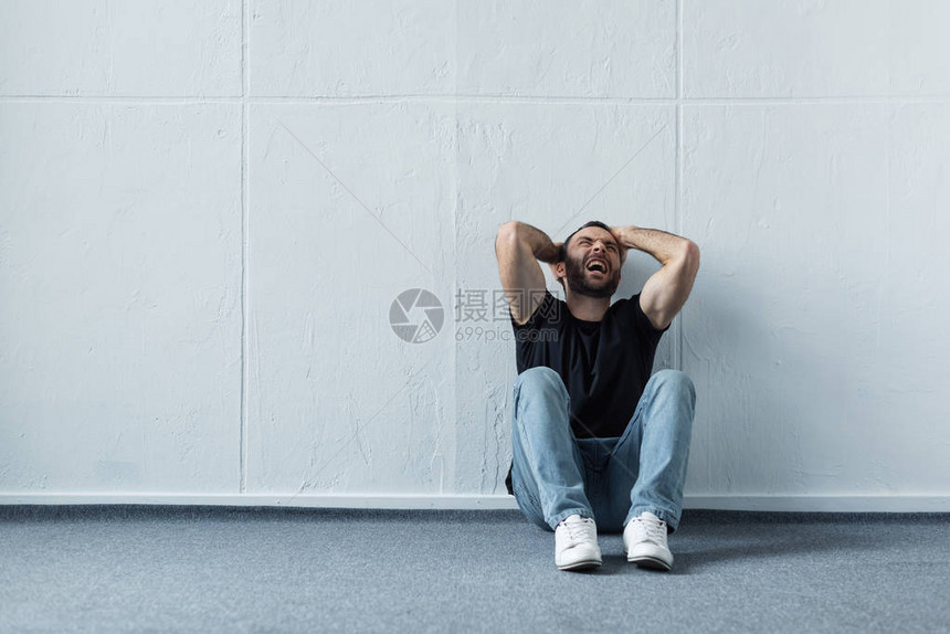 成人压抑症男子坐在白墙的图片