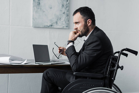 在工作场所坐轮椅的失望的残疾图片