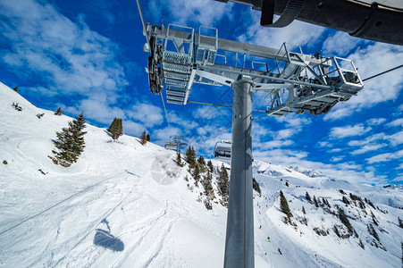 在白雪皑的山区滑雪缆车在明亮的阳光下图片