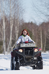 冬天的森林一个有姜色头发的女人骑着大红雪车冲图片