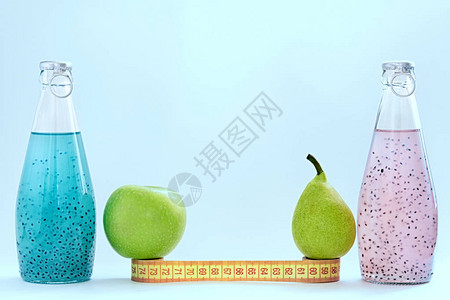 蓝色背景上矗立着一厘米一个苹果一个梨和一个玻璃瓶图片