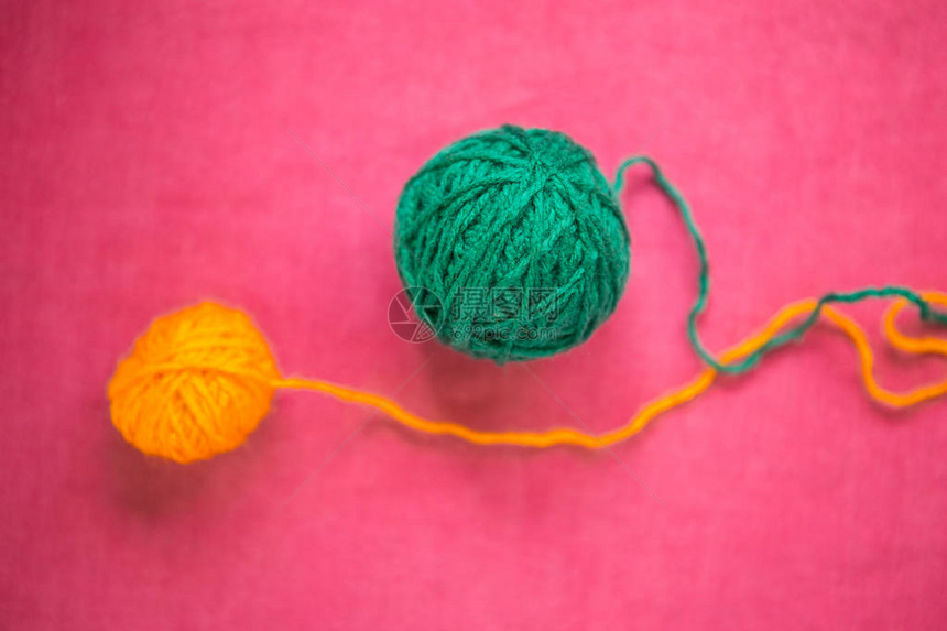 粉红背景的两球羊毛编织绿线和黄线两图片