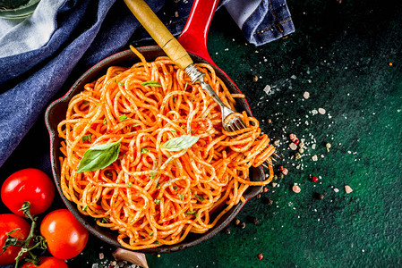 意大利午餐自制意大利面配经典的番茄酱香料大蒜罗勒在深绿色的混凝土桌图片