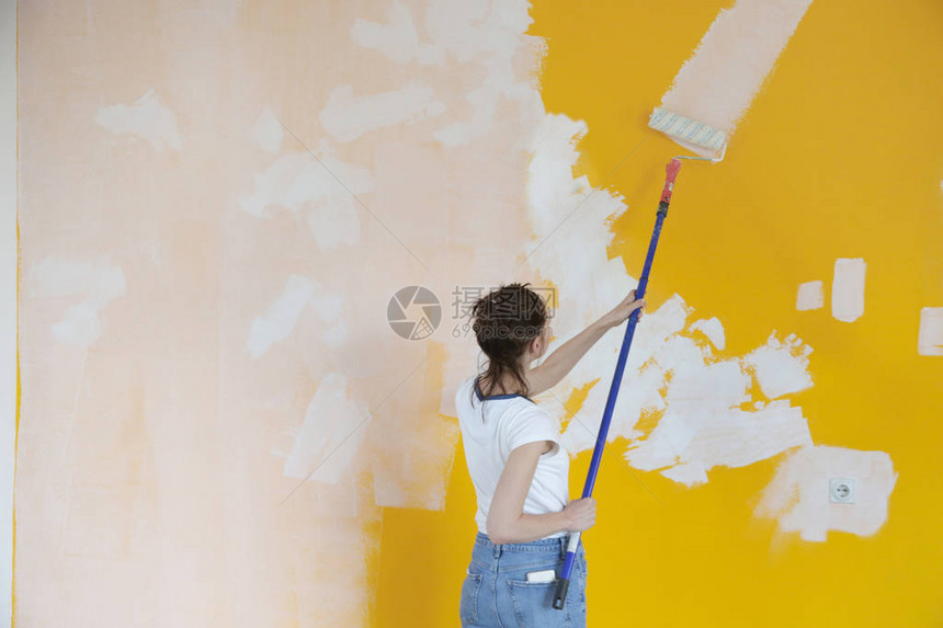 在黄墙上涂白漆的女人图片