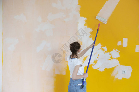 在黄墙上涂白漆的女人背景图片