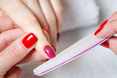 一名妇女在美甲沙龙接受美容师用指甲锉修指甲的特写镜头得到指甲图片