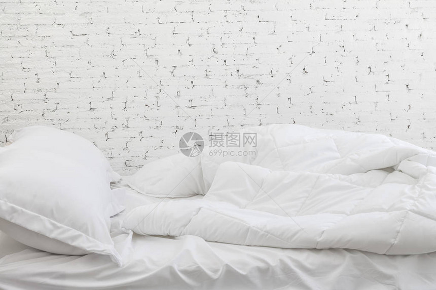 白床单和枕头都是白色房间背景的床上概念很乱图片