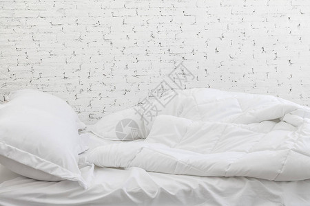 白床单和枕头都是白色房间背景的床上概念很乱图片