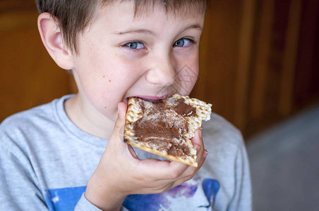 一个可爱的蓝眼睛孩子的特写肖像吃了一个配巧克图片