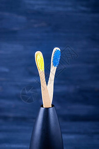深蓝色背景的明黄色和蓝竹牙刷生态友好概念最小化版面图片