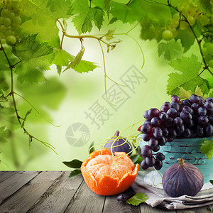 白色木桌背景上的水果和绿葡萄叶图片