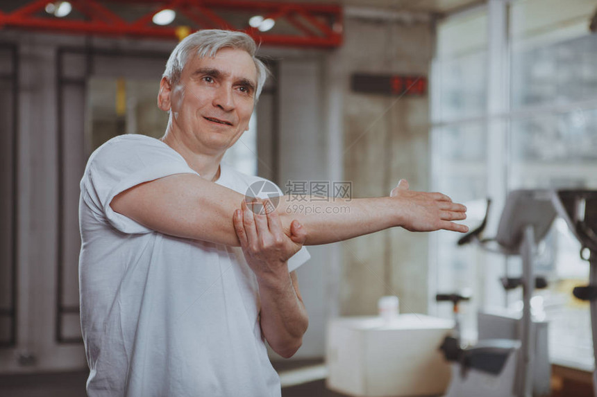 健康的老人在健身房锻炼前伸展他的肩膀和手臂快乐的老人早上在当地的体育工作室享受锻炼健图片
