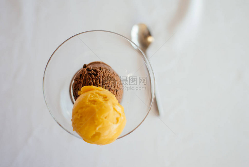 两勺冰淇淋芒果和巧克力在浅薄背景图片