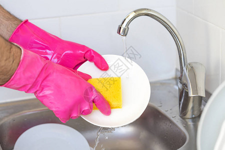 男人用泡沫手在屋子厨房里用洗涤剂和海绵洗陶瓷器图片