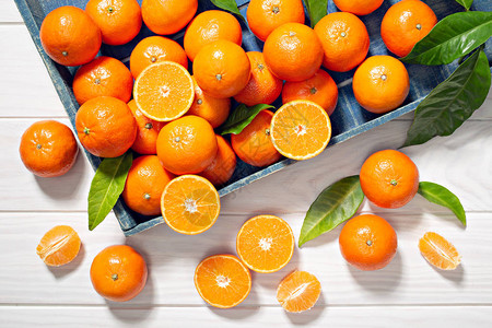 含木制餐桌叶子的新鲜橘子水果图片