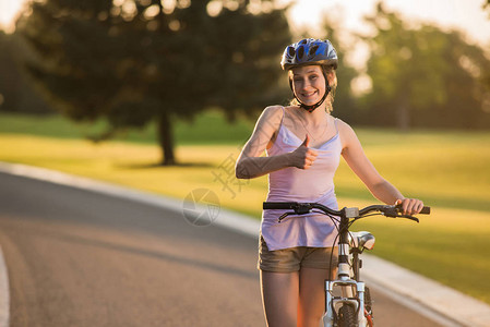 女骑自行车者在户外献出拇指图片