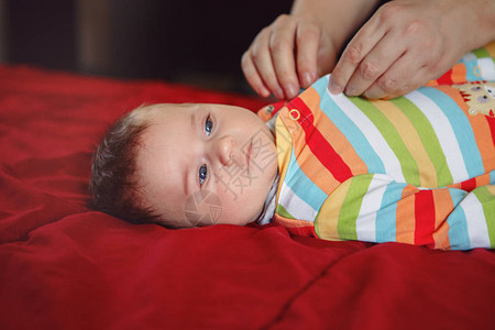 父母照顾者为躺在床上的新生男婴换尿布衣服爸妈在家照顾孩子真实的生活方图片