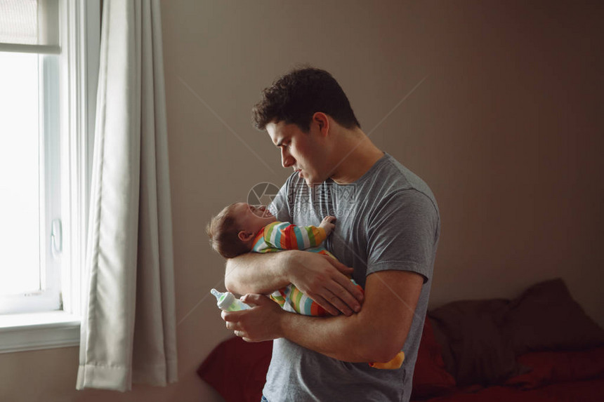 年轻的高加索父亲用牛奶喂养刚出生的婴儿子女儿男父母在他的手上抱着孩子真实的生活方式坦诚真实的时刻单身爸图片