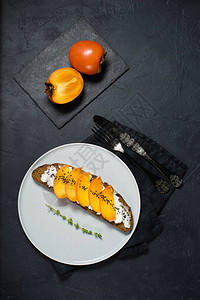 黑色背景中的柿子和软奶酪三明治图片