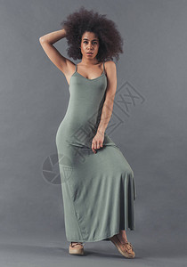 身着长裙散衣的非裔美洲妇女正用摄像头灰色背景图片