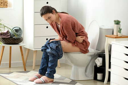 家中厕所碗上腹泻的年轻妇女在家里患图片