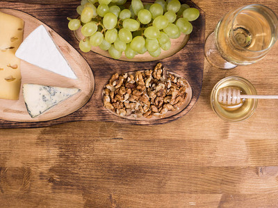 在木桌上放着蜂蜜的白葡萄酒的顶部视图法国奶酪美味的葡萄美味的蜂蜜图片