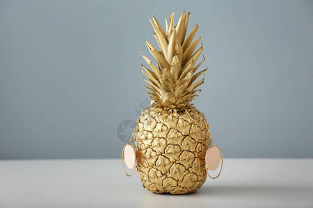 灰色背景下桌子上带耳环的菠萝图片