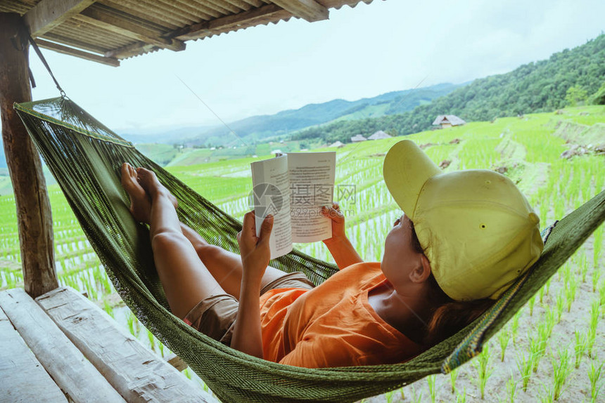亚洲女人旅行的质放松地在吊床上看书度假村的阳台夏季在山上的字图片