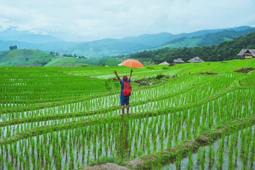 亚洲人旅行自然走在球场上打开一个雨伞背带包夏季在山上的字段视图稻图片