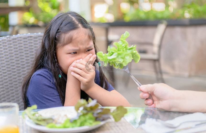 表示厌恶沙拉中的蔬菜拒绝食物概念的亚洲女童和年幼女孩图片