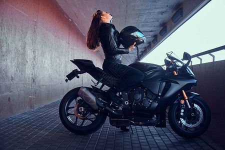 迷人的勇敢女人坐在地道上的摩托车上图片