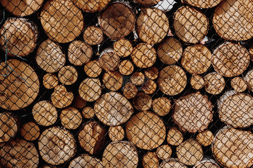 为生产木柴而准备的锯木在金属网格后面成排列木头位于图片