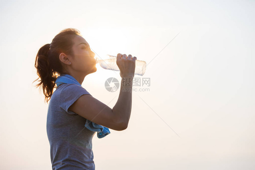 女人在运动后在阳光下拿着一瓶干净的水和饮料现代人的保健和良好生图片