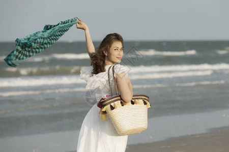 女携带大型手工艺袋在海滩玩耍时随风而行图片