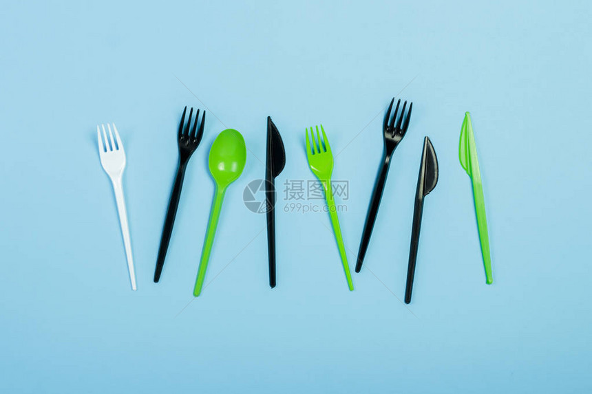 蓝色背景上的一次塑料餐具和食品用具叉子勺子和刀概念塑料图片