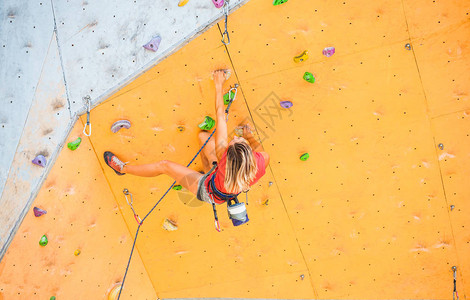 登山者在人工浮雕上训练一名妇女在街道攀岩墙上攀登岩路线在大厅训练参与体育运背景图片