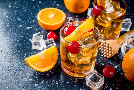 古典酒精鸡尾酒威士忌加冰块橙片和鸡尾酒红樱桃背景图片