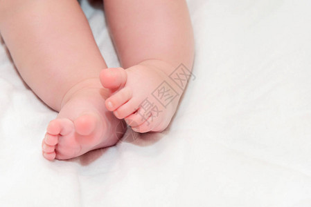 脚刚出生的婴儿放在白色的床罩上图片