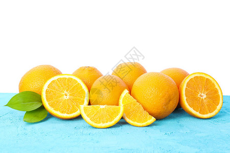 许多橙子在蓝色桌上有叶子白图片