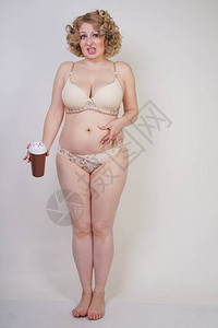 成年体重超的女人站在内衣里痛恨她的肚子和脂肪在工作图片