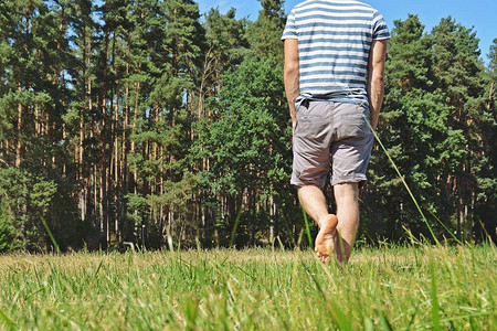 脚上特写男人在夏天穿过一片绿色的草地图片