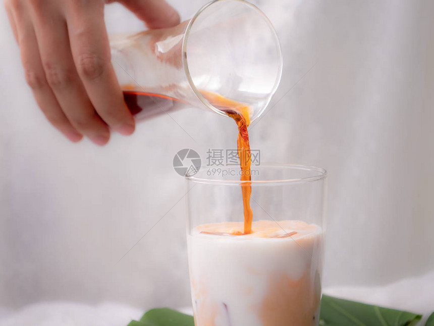 手握茶杯倒入牛奶中图片