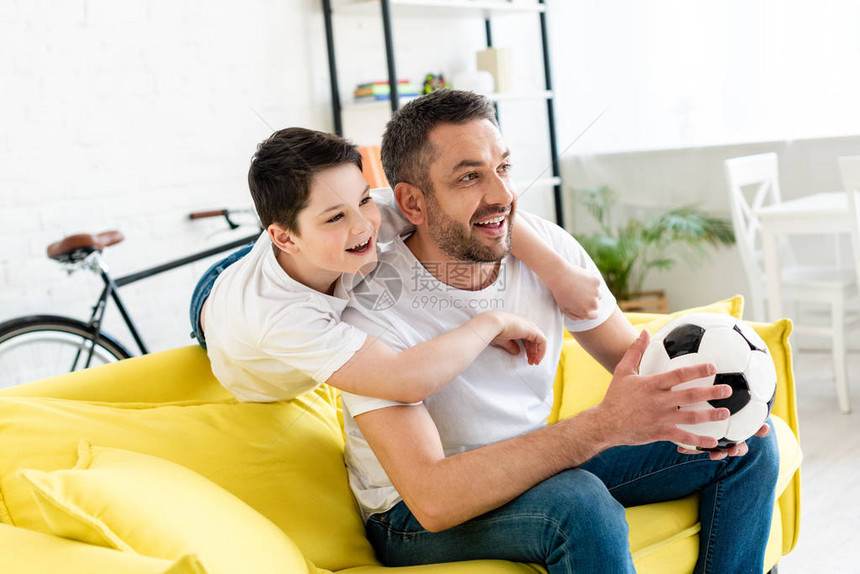 快乐的父亲和儿子在沙发上看体育比赛图片