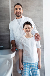 穿着睡衣的爸和儿子微笑在浴室图片