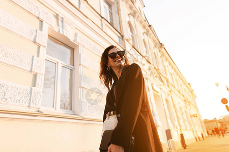 穿着时髦衣服戴着时髦太阳镜快乐的年轻时髦女人在城里走来去图片