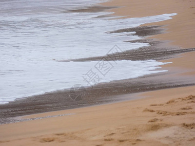 大浪拍打着海岸的沙子和岩石背景图片