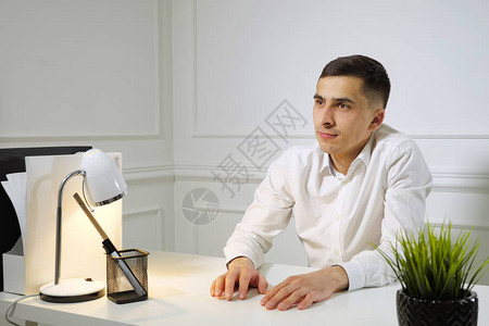 白衬衫办公室的青年工人在办公室办公桌坐着工作拖拉图片