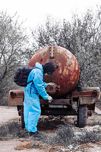 身穿蓝色防护服的男子在被毁的旧工厂测试脏水环境污染和生背景图片